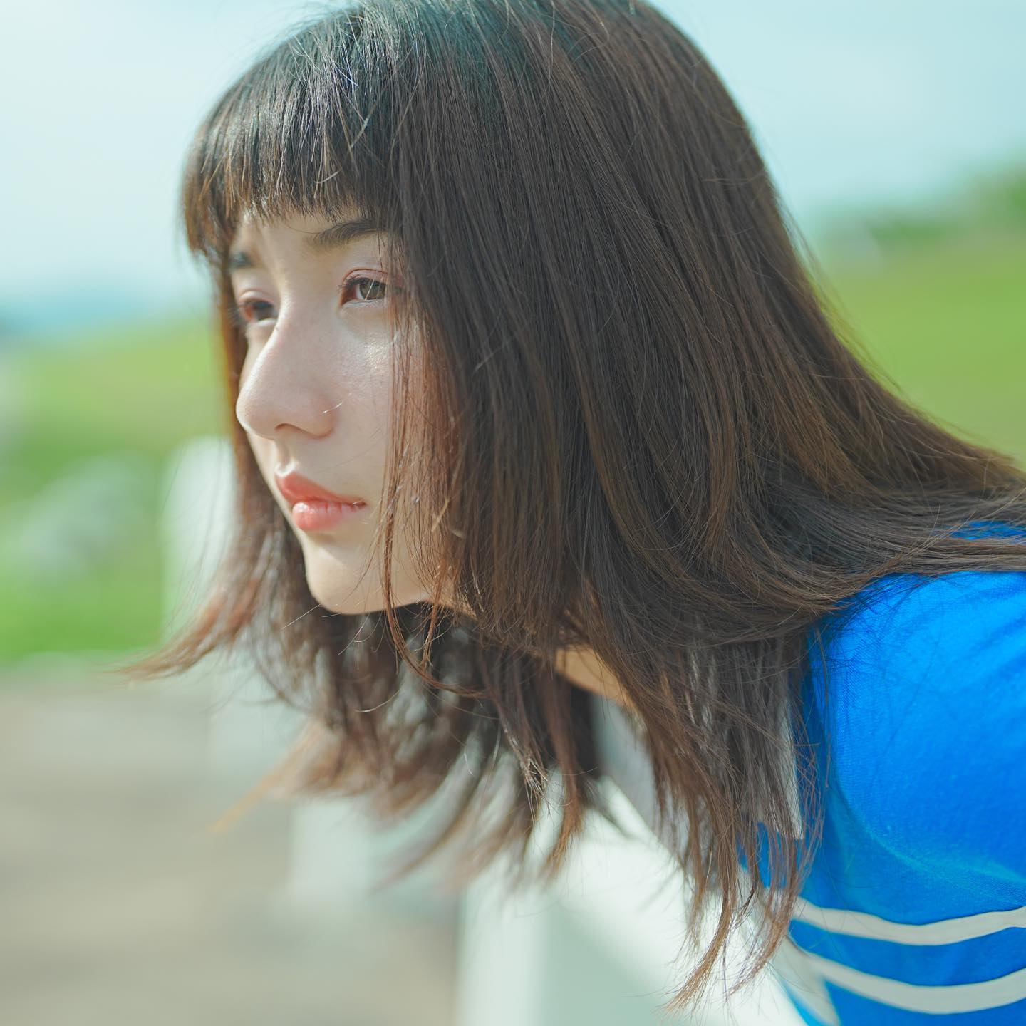 Close up side view of girl in a blue striped top leaning forward