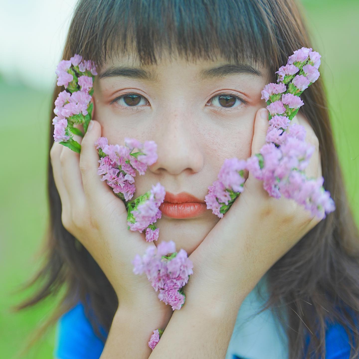 Close-up of girl with purple flowers in hands, framing her face