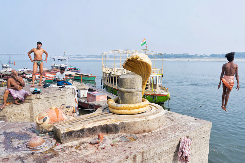 Indian men hanging around a pier, with one jumping into the water