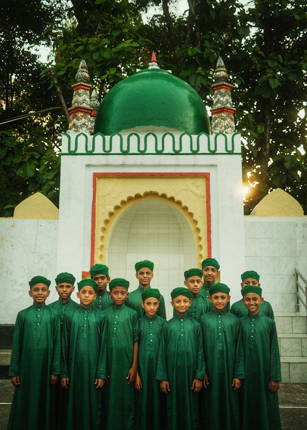 Group of students in green uniforms smiling in front of a domed structure