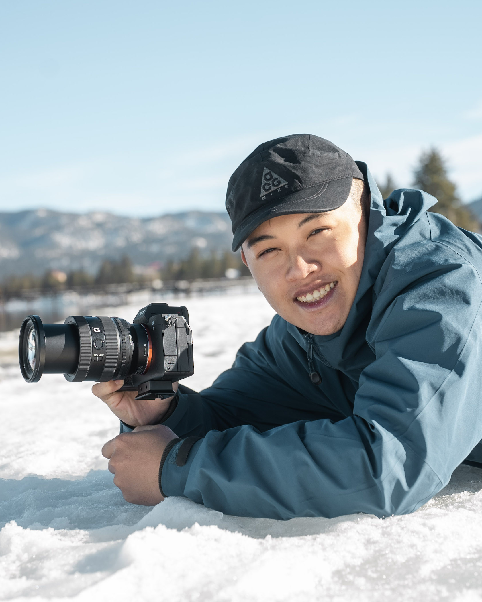 Photographer holding a camera and lying on the snow-covered surface to capture the shot