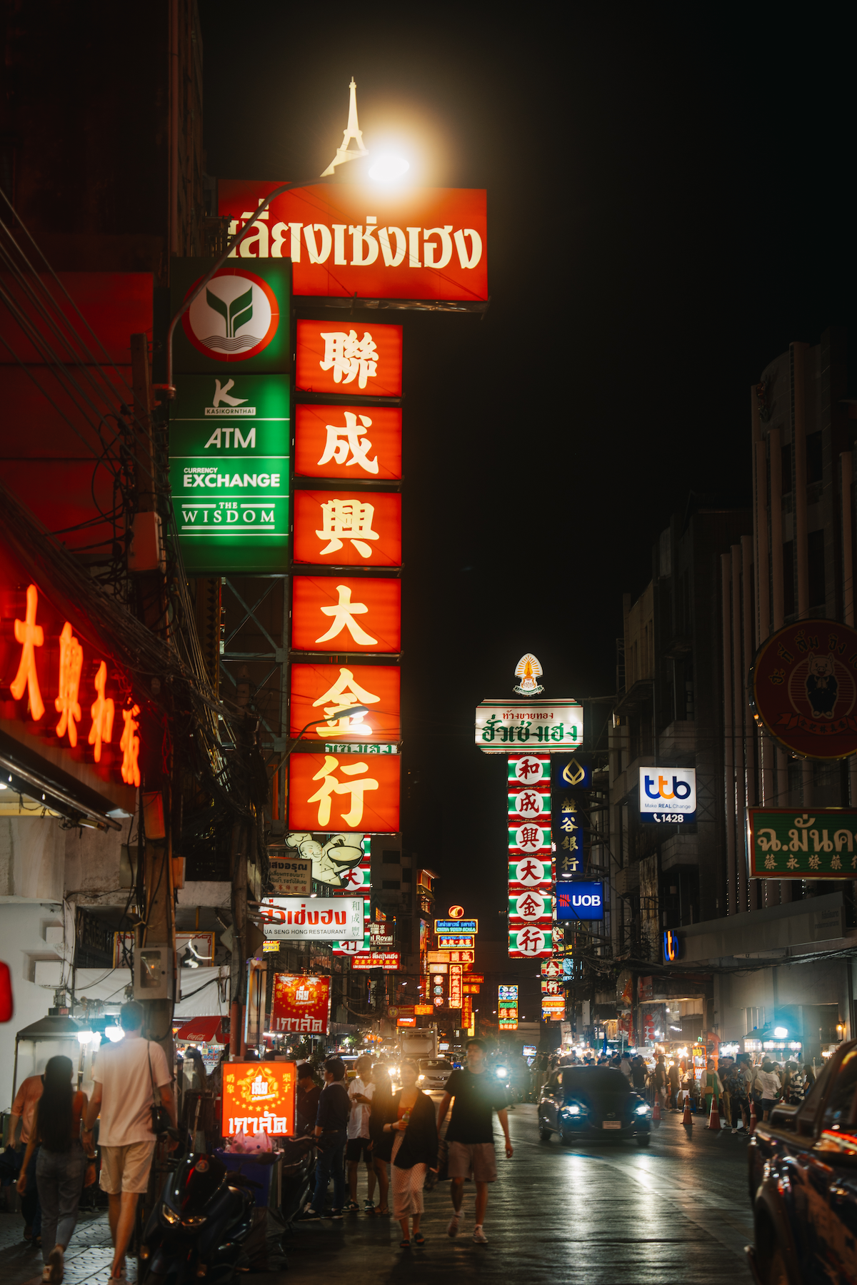 Busy street at night with bright store signages and many pedestrians