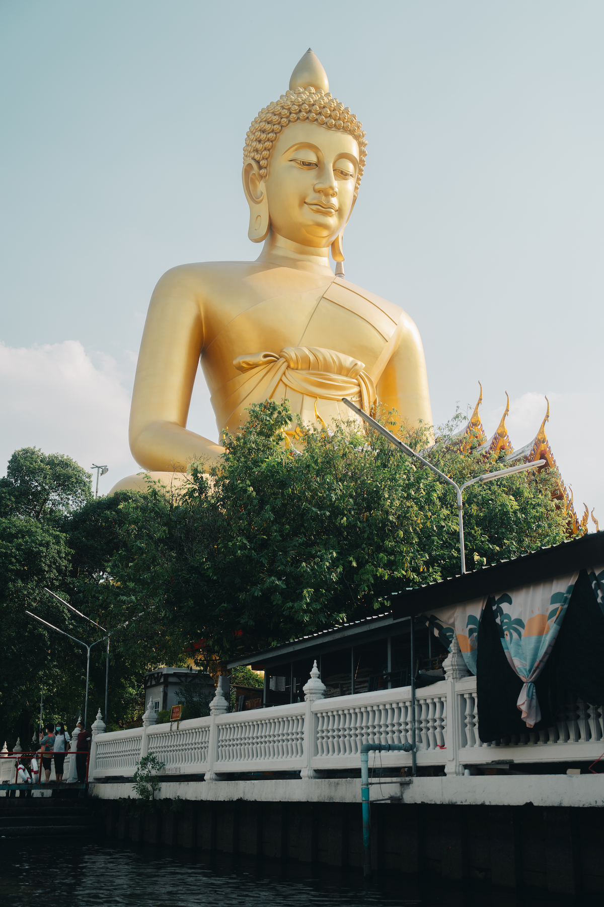 Low-angle view of a large golden Buddha statue from the river