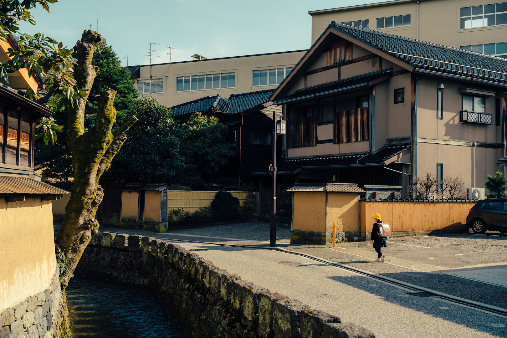 Young school girl walking home on a quiet street with Japanese-style houses in the background